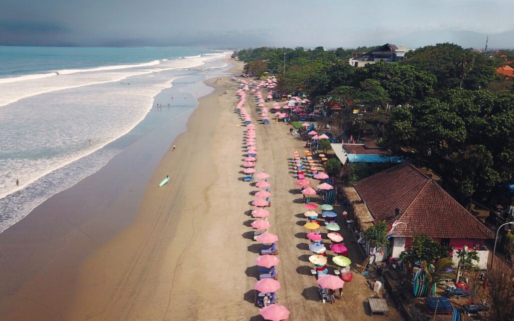 Aerial view of Seminyak beach with a long line of pink parasols.