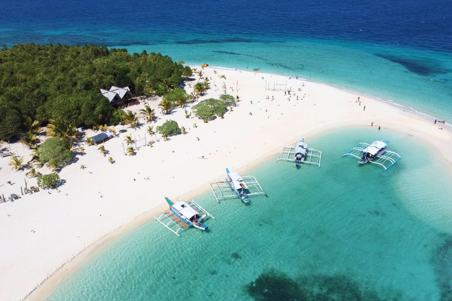 Traditional Philippine boats on Palawan Island with white sand and clear water