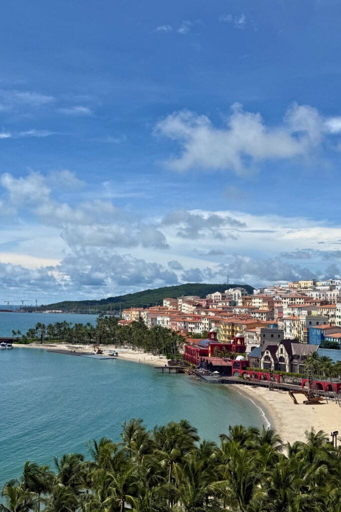 Scenic view of Phu Quoc's beaches with colorful town buildings and lush palm trees under a partly cl.