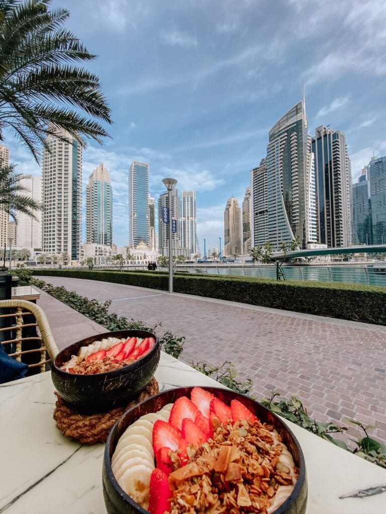 আধুনিক আকাশচুম্বী ভবন এবং সমুদ্র সৈকতের দৃশ্য সহ প্রাণবন্ত শহরের দৃশ্য দুবাই ভ্রমণকে উৎসাহিত করে।