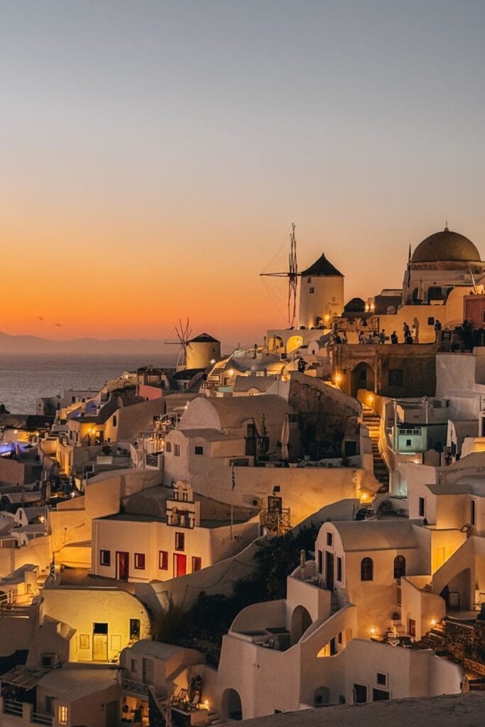 Santorini sunset with iconic windmills, charming white buildings, and breathtaking ocean views at dusk.