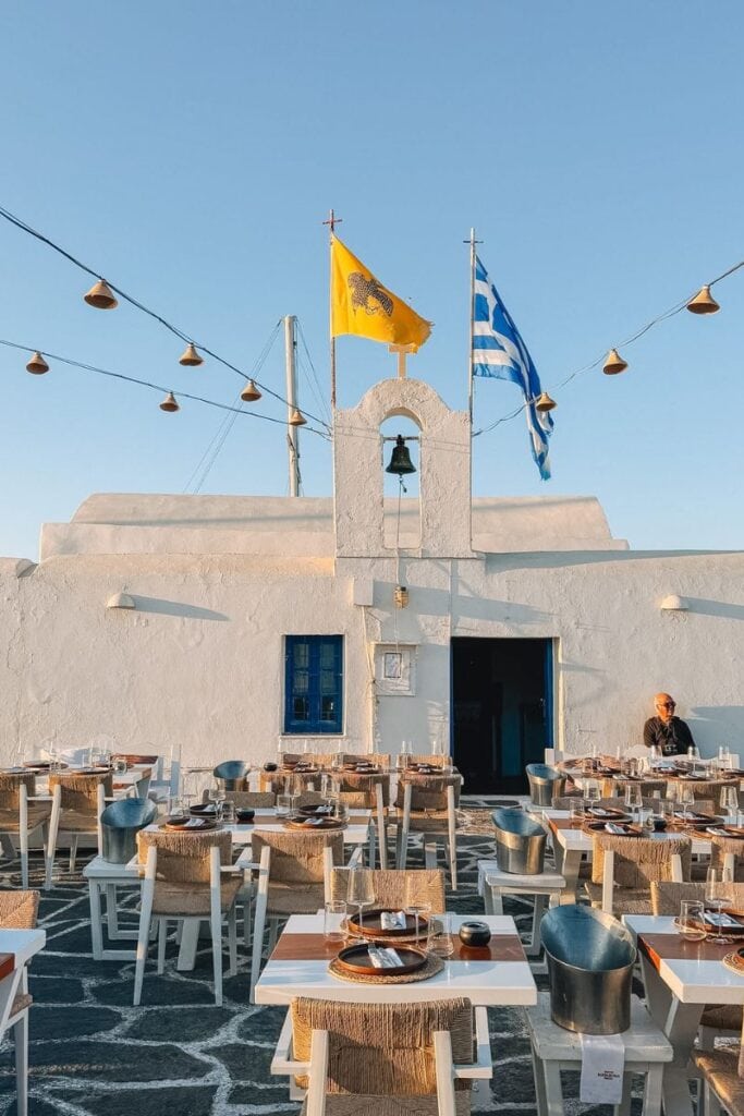 Traditional Greek taverna with outdoor seating in Paros, Greece, under a clear blue sky.