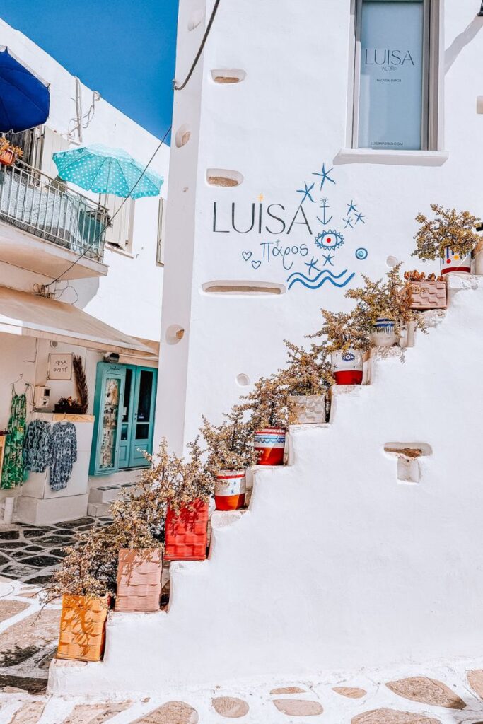 Charming white-washed building with colorful potted plants in Paros, Greece.