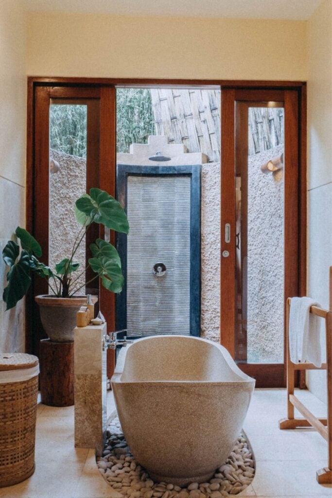Outdoor bathroom with stone bathtub and lush greenery in Munduk.