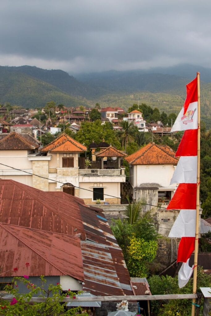 Munduk village scenery with traditional houses and lush green mountains in the background.