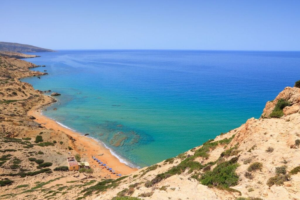 A lush, secluded beach with turquoise waters and sandy shores, surrounded by rocky cliffs and clear.