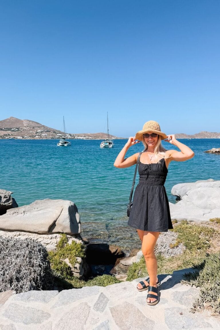 Relaxing woman enjoying a sunny day by the sea with boats in the background, wearing a hat and summe.